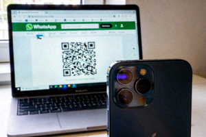 手机摄像头正在扫描电脑屏幕上显示的WhatsApp网页版二维码